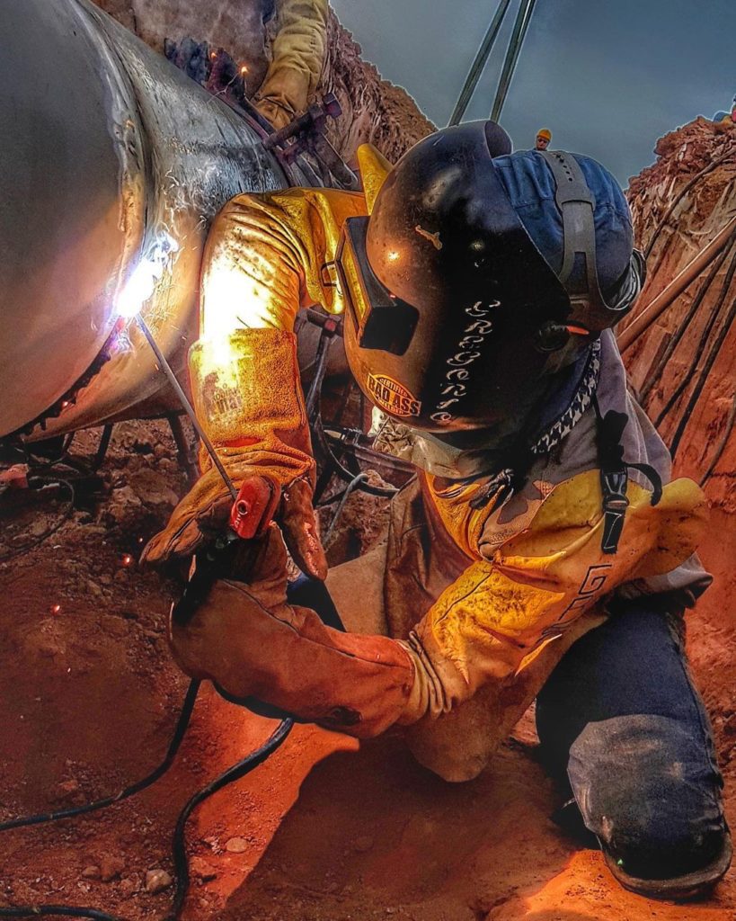 Un soudeur a l'arc sur un pipe.